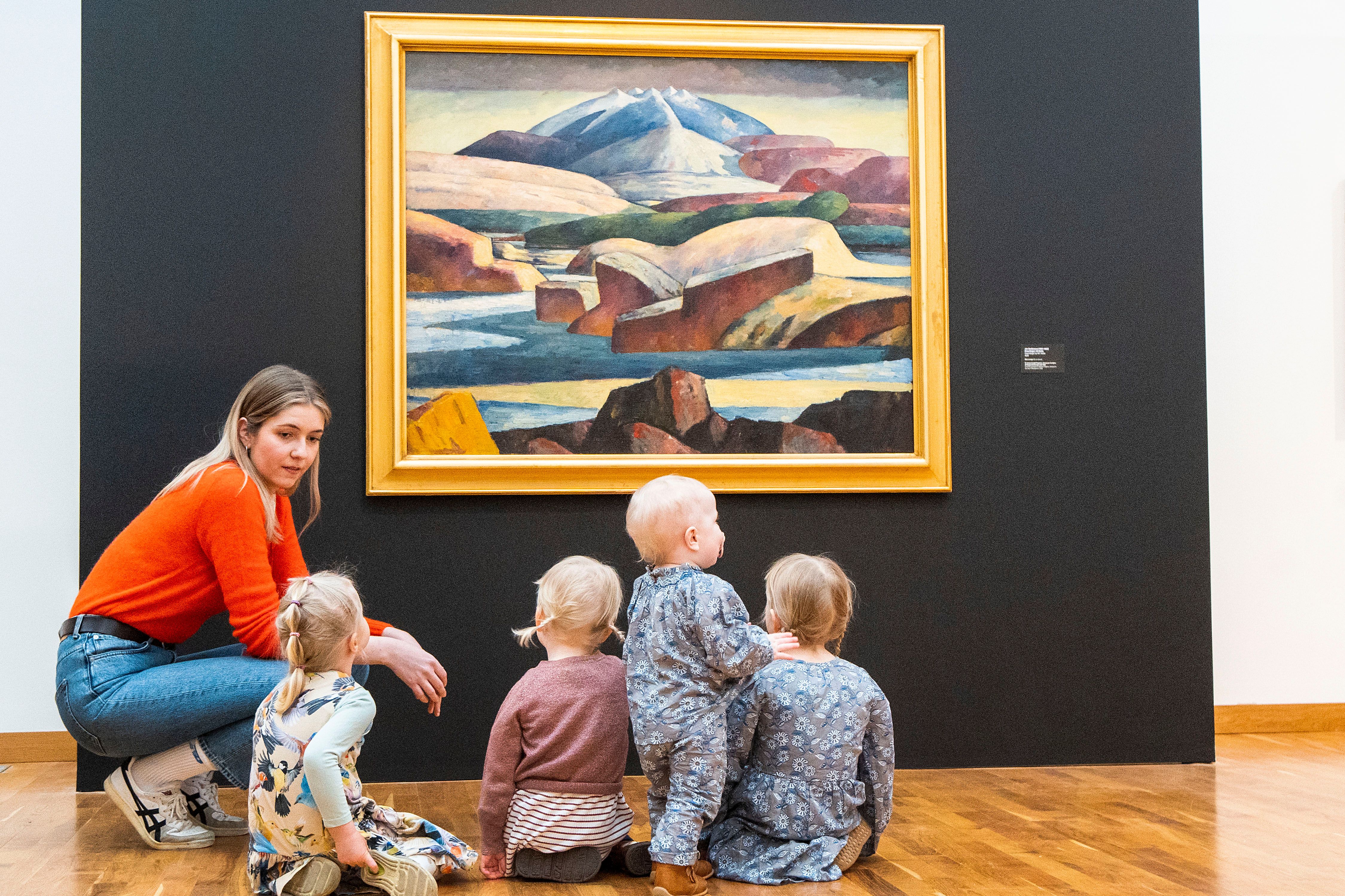 Ljósmynd af konu og börnum skoða listaverk